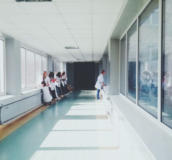 Corredor hospitalar bem iluminado, com profissionais de saúde usando jalecos ao fundo.