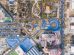 Vista aérea de um parque urbano com áreas de lazer, estacionamento e prédios ao redor