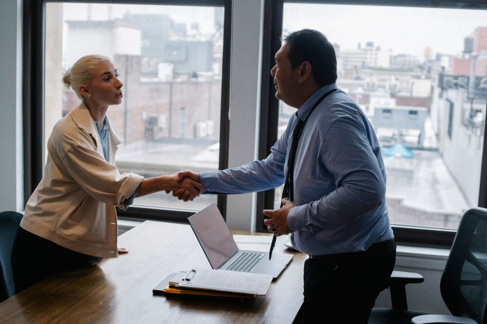 Candidata cumprimenta um empregador antes de uma entrevista de emprego em um escritório.