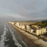 Vista aérea da faixa litorânea de Mongaguá, com praia e área urbana formada por edifícios residenciais.