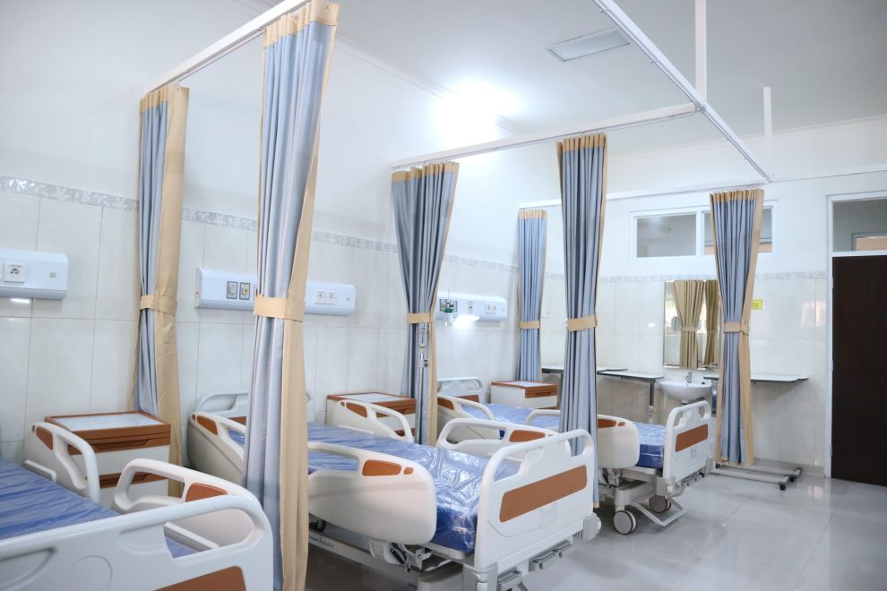 Ala hospitalar ampla e moderna, com equipamentos médicos e áreas individuais para pacientes.