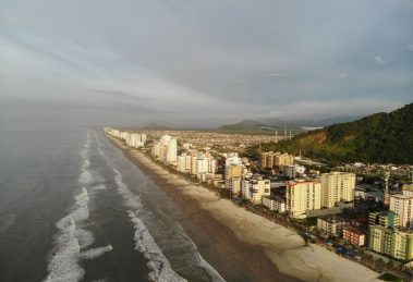 Vista aérea da faixa litorânea de Mongaguá, com praia e área urbana formada por edifícios residenciais.