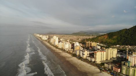 Vista aérea da faixa litorânea de Mongaguá, com praia e área urbana formada por edifícios residenciais.