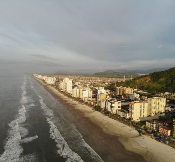 Vista aérea da faixa litorânea de Mongaguá, com praia e área urbana formada por edifícios residenciais.