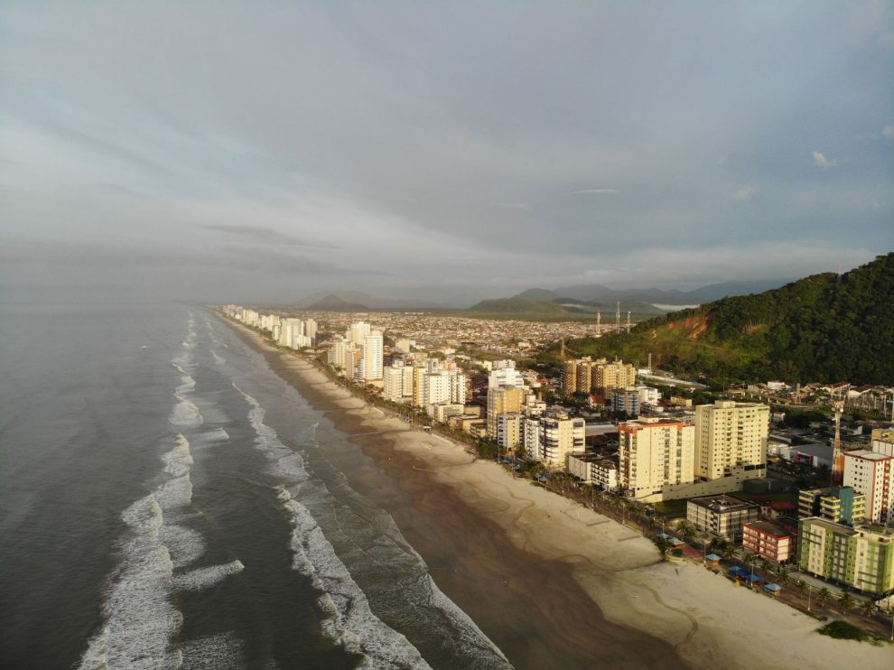 Vista aérea da faixa litorânea de Mongaguá, com praia e área urbana formada por edifícios residenciais.